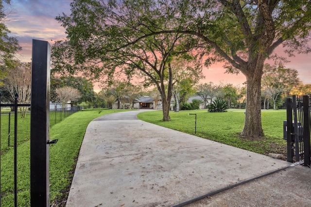 surrounding community with a lawn, driveway, and fence