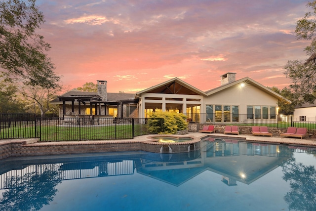 pool at dusk featuring an in ground hot tub and a patio area