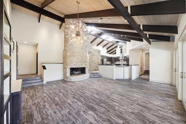 unfurnished living room with dark wood-style floors, an outdoor stone fireplace, an inviting chandelier, high vaulted ceiling, and beamed ceiling