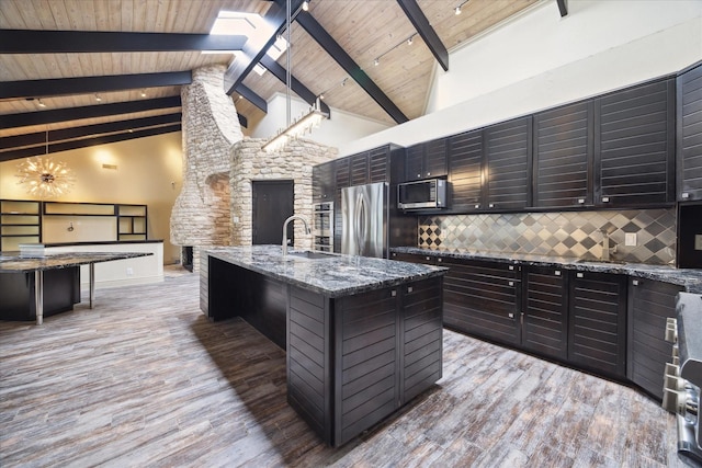 kitchen with appliances with stainless steel finishes, a sink, light wood finished floors, and tasteful backsplash