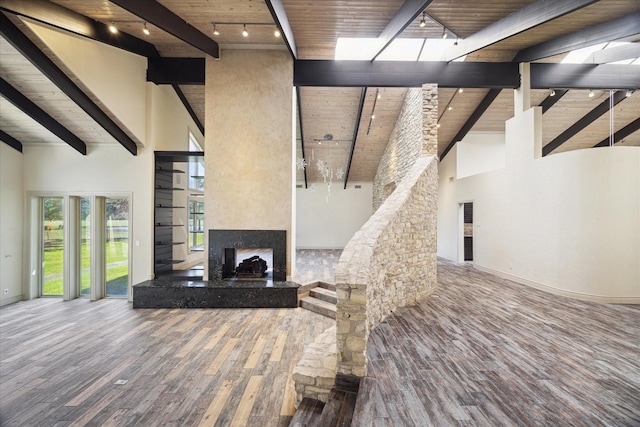 unfurnished living room with beam ceiling, a fireplace with raised hearth, wood ceiling, wood finished floors, and high vaulted ceiling