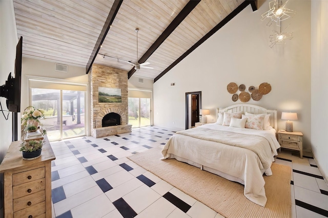 bedroom featuring access to exterior, beam ceiling, a stone fireplace, high vaulted ceiling, and baseboards