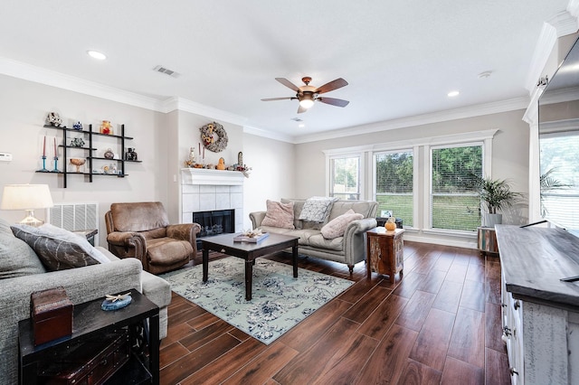 living room featuring ceiling fan, crown molding, and a tiled fireplace