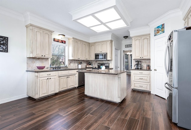 kitchen with appliances with stainless steel finishes, a center island, cream cabinets, and sink