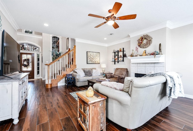 living room with dark hardwood / wood-style floors, ceiling fan, ornamental molding, and a tiled fireplace