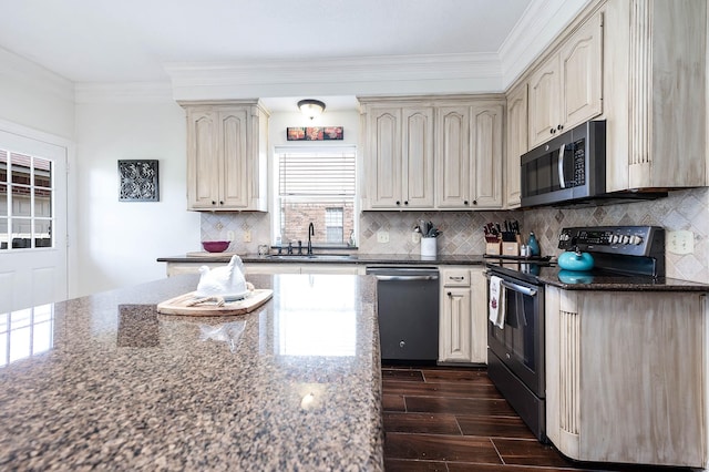 kitchen featuring sink, stainless steel appliances, dark stone counters, and cream cabinets