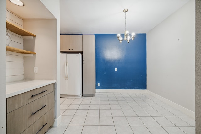 kitchen featuring light brown cabinets, hanging light fixtures, a notable chandelier, white refrigerator, and light tile patterned floors