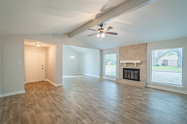 unfurnished living room featuring hardwood / wood-style floors, ceiling fan, a healthy amount of sunlight, and lofted ceiling with beams