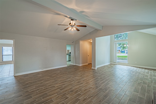 interior space with a healthy amount of sunlight, lofted ceiling with beams, ceiling fan, and dark wood-type flooring