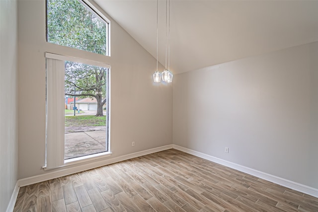 empty room with hardwood / wood-style flooring, a notable chandelier, and high vaulted ceiling