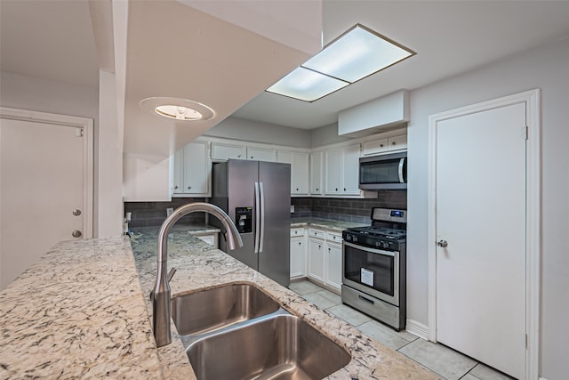 kitchen featuring sink, appliances with stainless steel finishes, tasteful backsplash, light stone counters, and white cabinetry