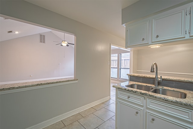 kitchen with lofted ceiling, sink, ceiling fan, light tile patterned floors, and white cabinetry