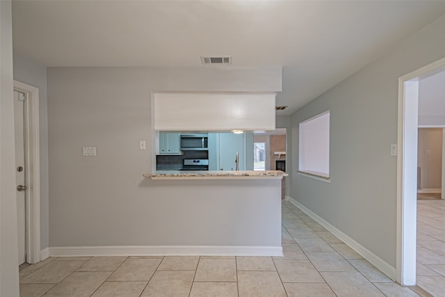 kitchen featuring white cabinetry, tasteful backsplash, kitchen peninsula, stove, and light tile patterned flooring