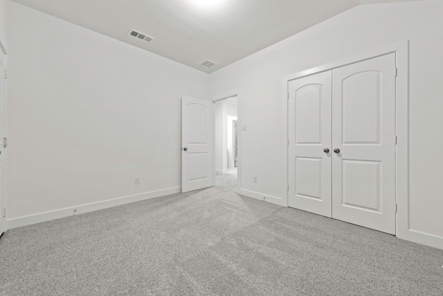 unfurnished bedroom with lofted ceiling, light carpet, and a closet