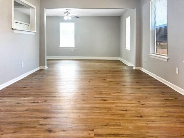 empty room featuring a wealth of natural light, ceiling fan, and hardwood / wood-style floors