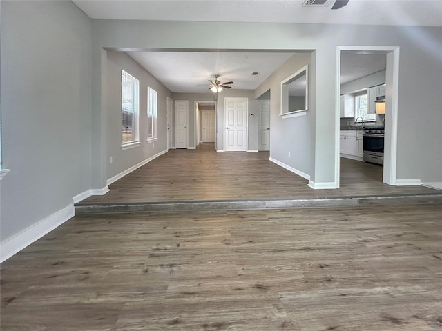 unfurnished living room featuring ceiling fan and dark hardwood / wood-style flooring