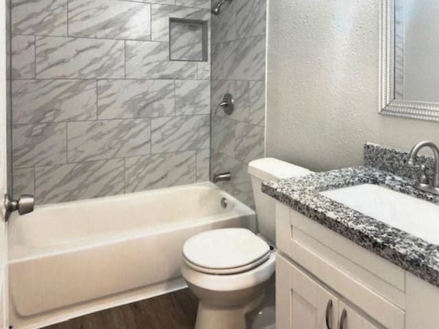 full bathroom featuring hardwood / wood-style floors, vanity, toilet, and tiled shower / bath