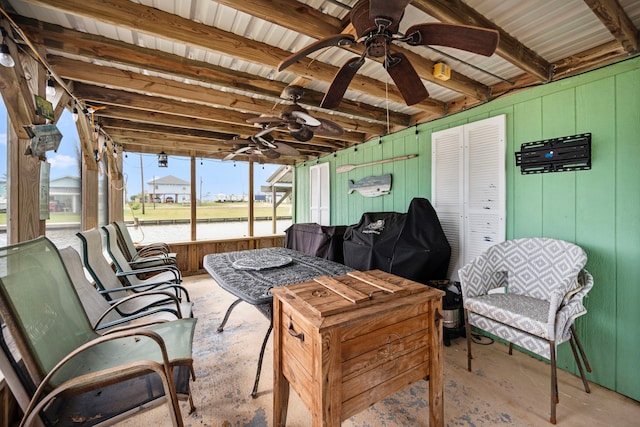 sunroom with ceiling fan and beamed ceiling