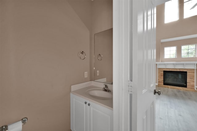 bathroom with a fireplace, vanity, wood-type flooring, and lofted ceiling