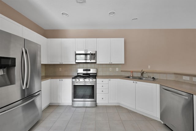 kitchen with white cabinetry, sink, stainless steel appliances, decorative backsplash, and light tile patterned flooring