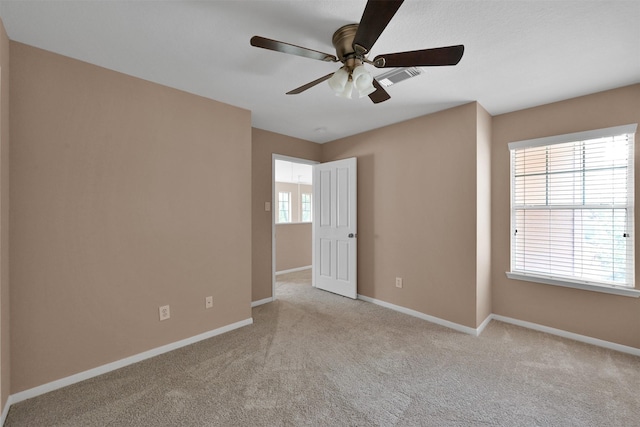 spare room featuring light carpet, ceiling fan, and a healthy amount of sunlight