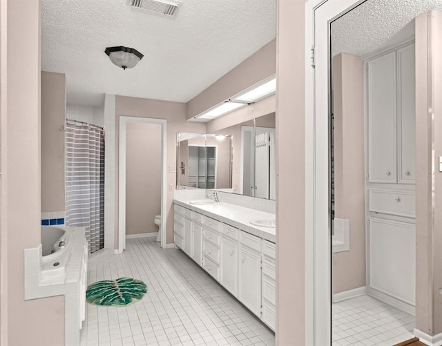 full bathroom with tile patterned flooring, vanity, a textured ceiling, and toilet