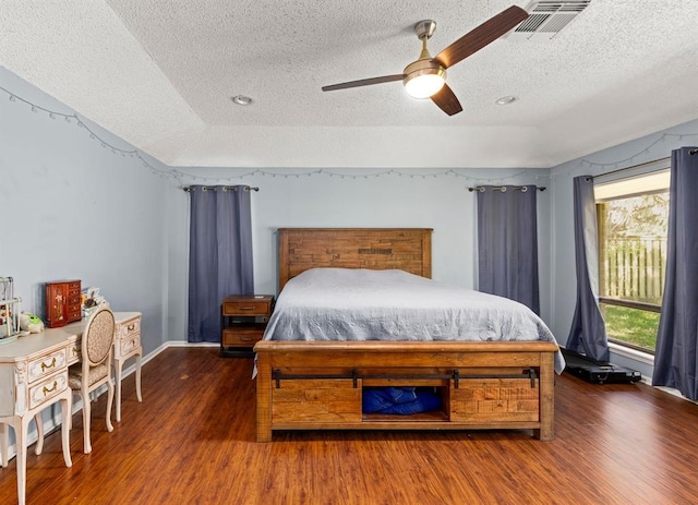 bedroom featuring dark hardwood / wood-style floors, ceiling fan, and a textured ceiling