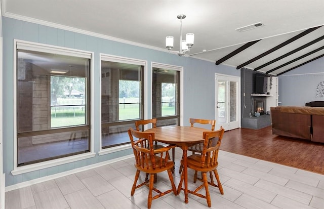 dining room with lofted ceiling with beams, a fireplace, light wood-type flooring, and ornamental molding