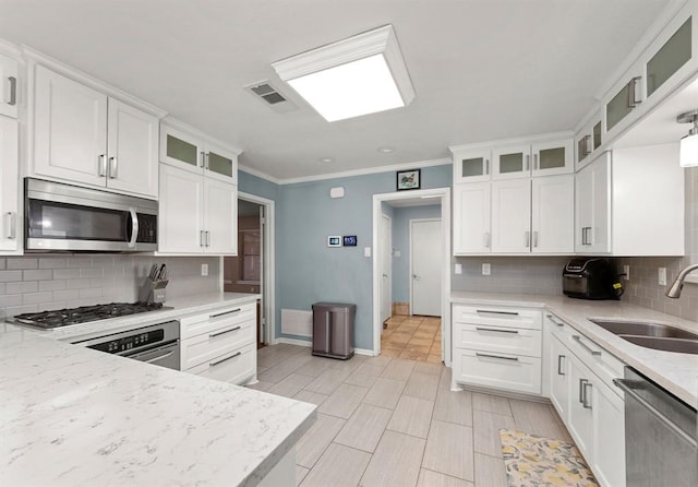 kitchen featuring backsplash, sink, light stone countertops, white cabinetry, and stainless steel appliances