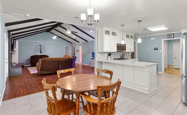 dining area featuring lofted ceiling with beams, ceiling fan with notable chandelier, and light hardwood / wood-style flooring