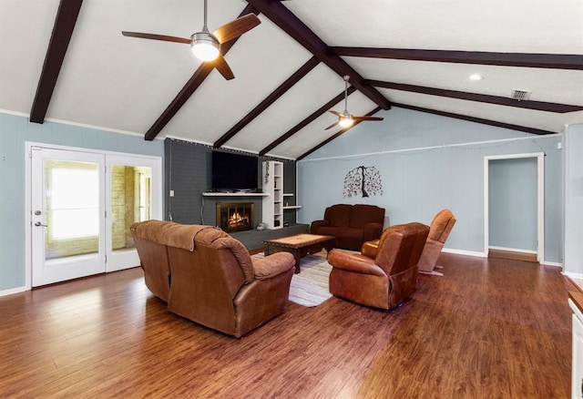 living room featuring wood-type flooring, vaulted ceiling with beams, a brick fireplace, and ceiling fan