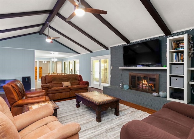 living room featuring vaulted ceiling with beams, ceiling fan, wood-type flooring, and a brick fireplace