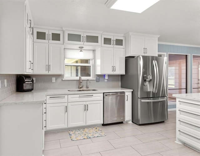 kitchen featuring light stone counters, stainless steel appliances, crown molding, sink, and white cabinetry