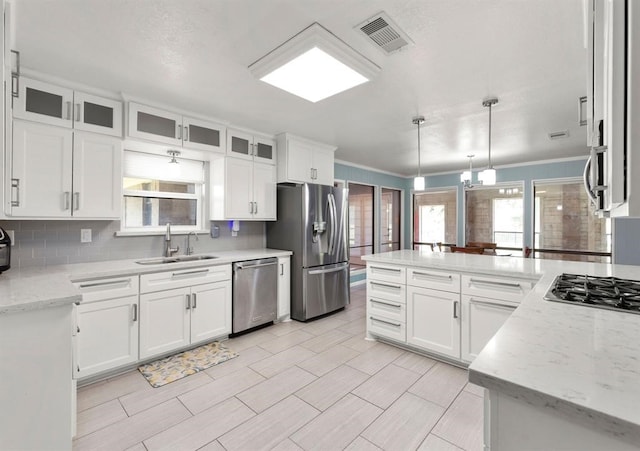 kitchen featuring white cabinets, sink, hanging light fixtures, light stone counters, and stainless steel appliances