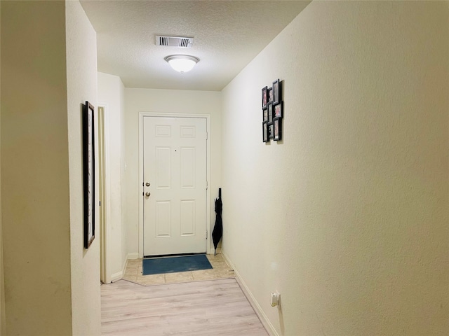 entryway with light hardwood / wood-style floors and a textured ceiling