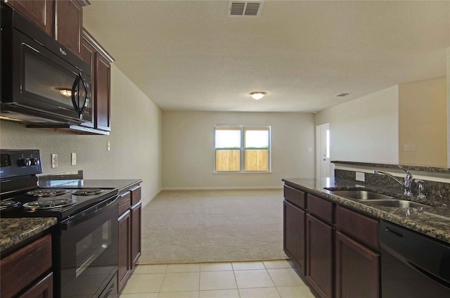 kitchen with sink, light colored carpet, dark stone counters, and black appliances