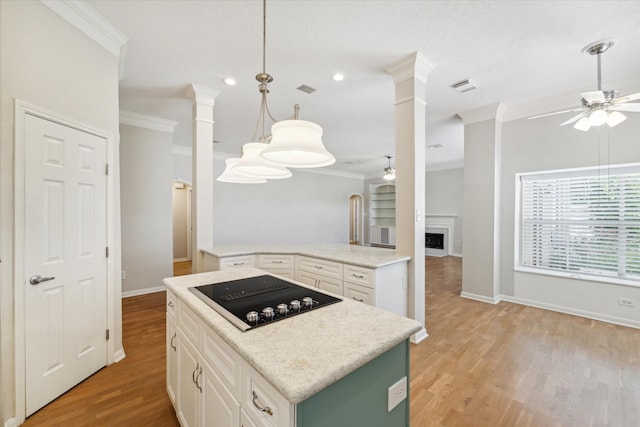 kitchen with black electric stovetop, white cabinets, crown molding, light hardwood / wood-style flooring, and ornate columns