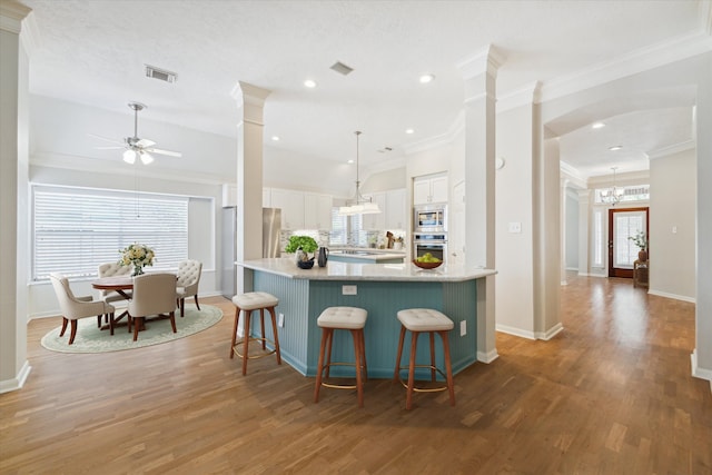 kitchen featuring white cabinetry, stainless steel appliances, hanging light fixtures, dark hardwood / wood-style flooring, and ceiling fan with notable chandelier