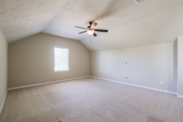 additional living space with ceiling fan, light colored carpet, and vaulted ceiling