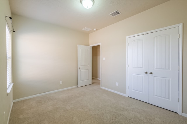 unfurnished bedroom with light carpet and a closet