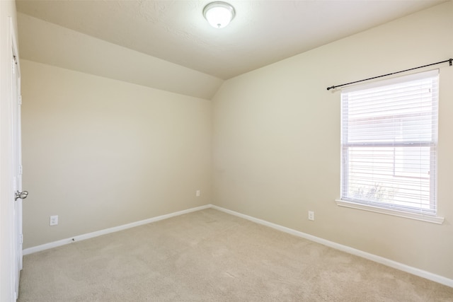 carpeted spare room featuring a healthy amount of sunlight and lofted ceiling