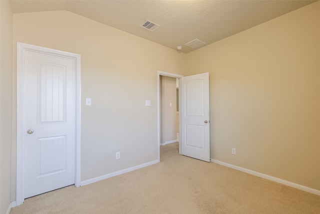 unfurnished bedroom featuring light colored carpet and vaulted ceiling