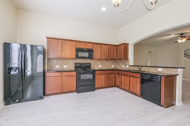 kitchen with sink, black appliances, ceiling fan with notable chandelier, and light hardwood / wood-style flooring