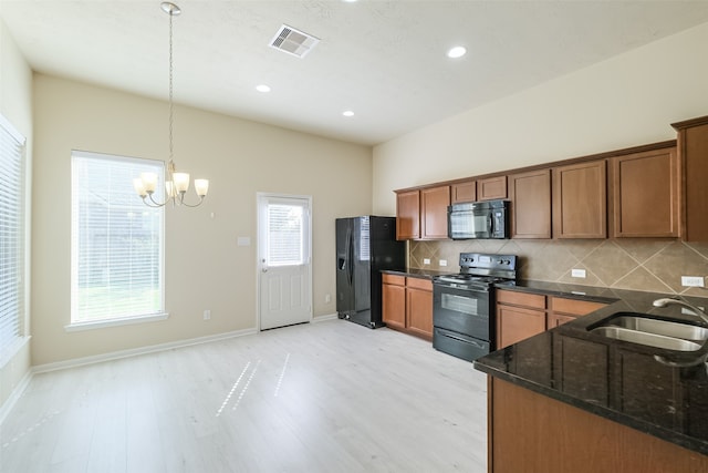 kitchen with pendant lighting, black appliances, sink, light wood-type flooring, and a chandelier