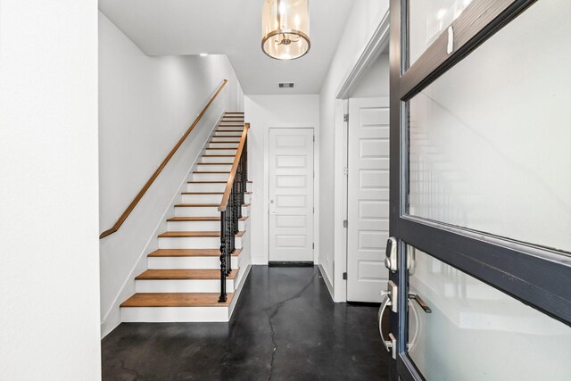 stairs with concrete flooring and an inviting chandelier