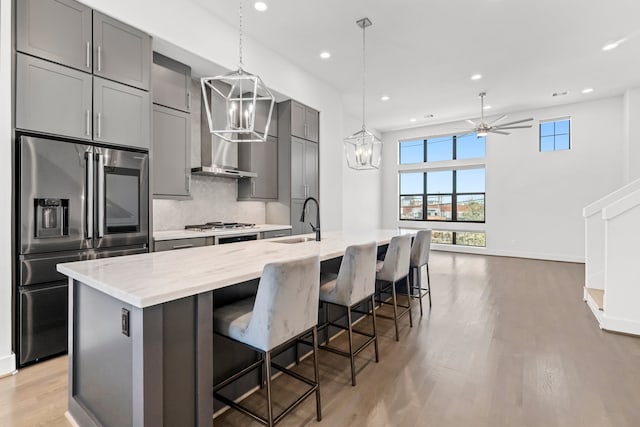 kitchen with stainless steel fridge, a center island with sink, light hardwood / wood-style flooring, and sink