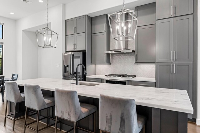 kitchen featuring a kitchen bar, light stone countertops, sink, gray cabinets, and a large island