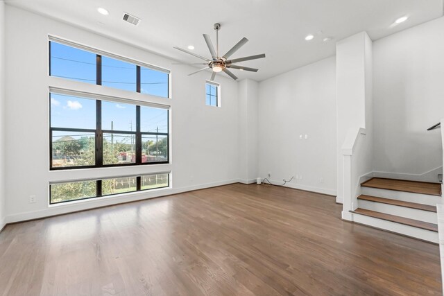 unfurnished living room featuring plenty of natural light, ceiling fan, and dark wood-type flooring