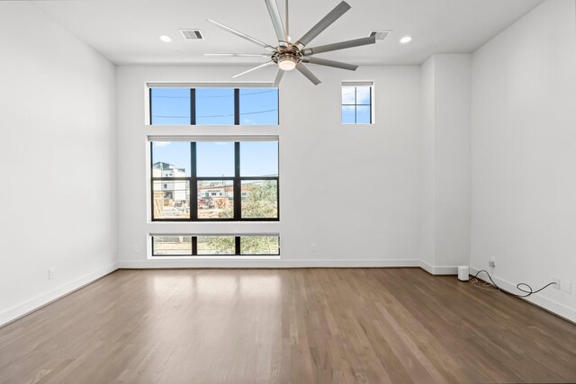 empty room with ceiling fan, a healthy amount of sunlight, and wood-type flooring