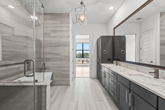 bathroom featuring a notable chandelier, vanity, and shower with separate bathtub